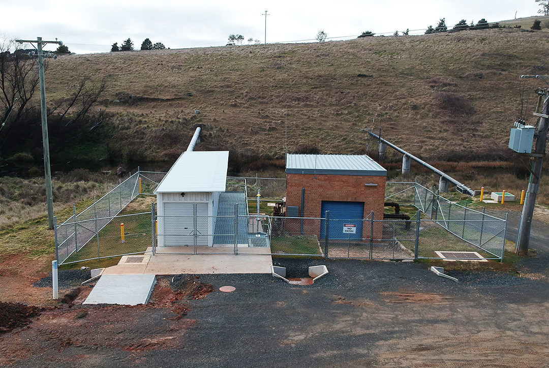 The completed Fish River dosing plant sits within a fenced area with a hill in the background.